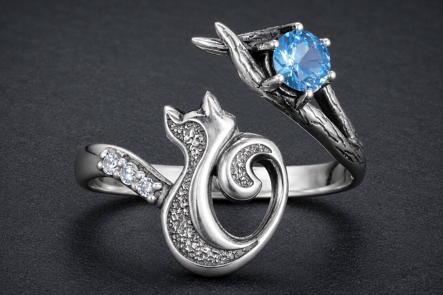 Silver cat ring with blue topaz stone cradled in branch details and wrap design