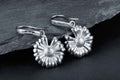 Silver daisy drop earrings with detailed petals and secure hoop closures