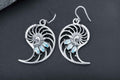 Sterling silver nautilus shell earrings with blue cubic zirconia stones and intricate spiral design