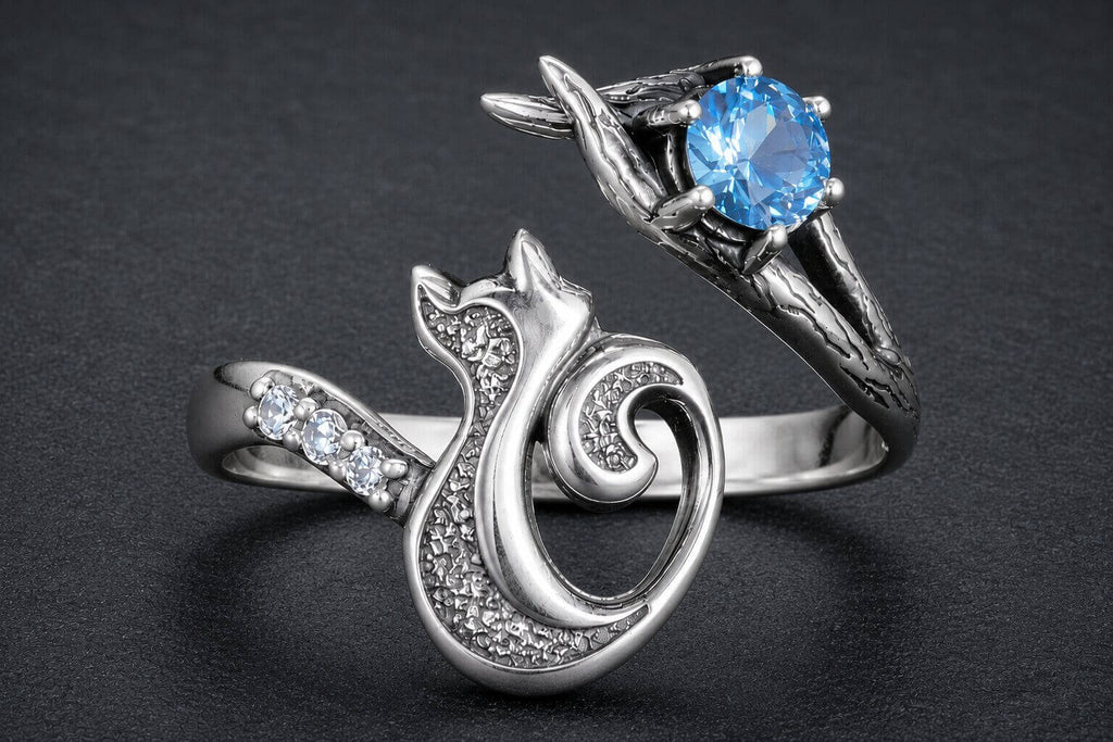 Sterling silver cat wrap ring with blue cubic zirconia stone cradled in branch details and spiral tail design