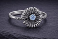 Sterling silver daisy ring with blue cubic zirconia center stone and detailed curved petal design
