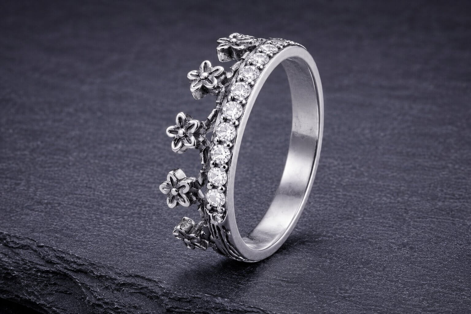 Sterling silver flower crown ring with detailed textured petals and cubic zirconia stone band