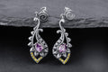 Silver lotus drop earrings with purple cubic zirconia center stone, golden accent stones, and spiral design