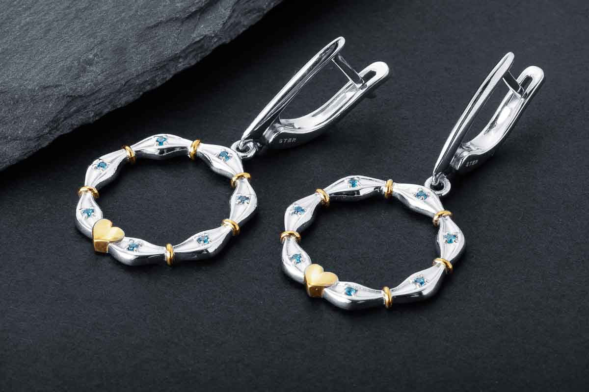 Two tone heart hoop earrings in sterling silver with gold accents and blue cubic zirconia stones